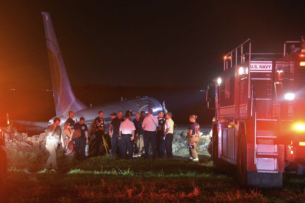 Emergency crews working next to a Boeing 737 aircraft arriving from Naval Station Guantanamo Bay, Cuba, which slid off the runway at Naval Air Station Jacksonville, Fla., into the St. Johns River. (Thomas A. Higgins/U.S. Navy via AP)