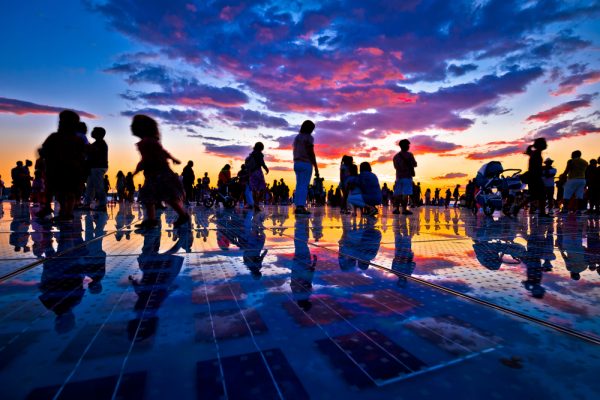 people silhouetted in sunset over zadar sun salutation