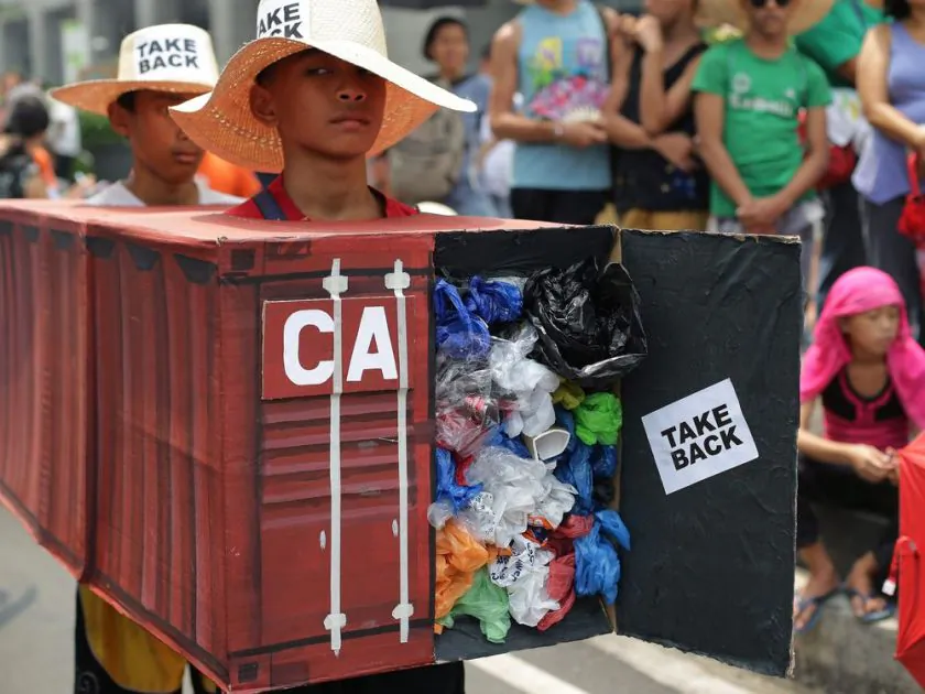 Filipino environmental activists wear a mock container vans filled with garbage to symbolize the 50 containers of waste that were shipped from Canada to the Philippines two years ago, at the Canadian embassy in Makati, south of Manila, Philippines, on May 7, 2015. (Aaron Favila/The Associated Press)