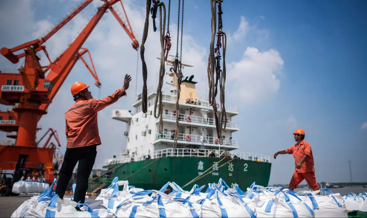 Workers unload bags of chemicals at a port in Zhangjiagang in China's eastern Jiangsu province on Aug. 7, 2018. (Johannes Eisele/AFP/Getty Images)