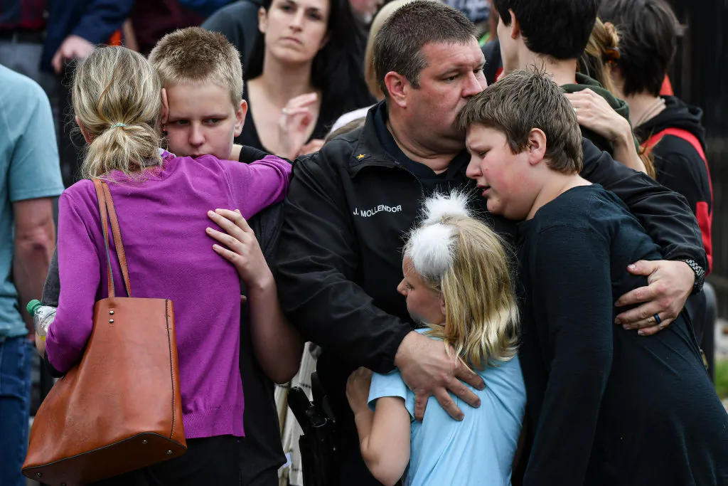A police officer hugs his children after they were evacuated to the Recreation Center at Northridge after at least seven students were injured during a shooting at STEM School Highlands Ranch in Highlands Ranch, Colorado, on May 7, 2019. (Michael Ciaglo/Getty Images)