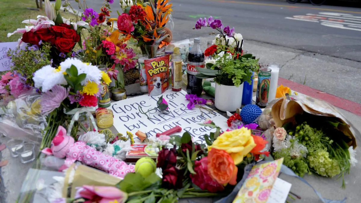 Photo flowers and cards rest on a memorial for Jessica Bingaman on May 8, 2019, a popular dog walker, who was killed along with five of six dogs she was transporting in Long Beach, Calif. (Brittany Murray/The Orange County Register via AP)