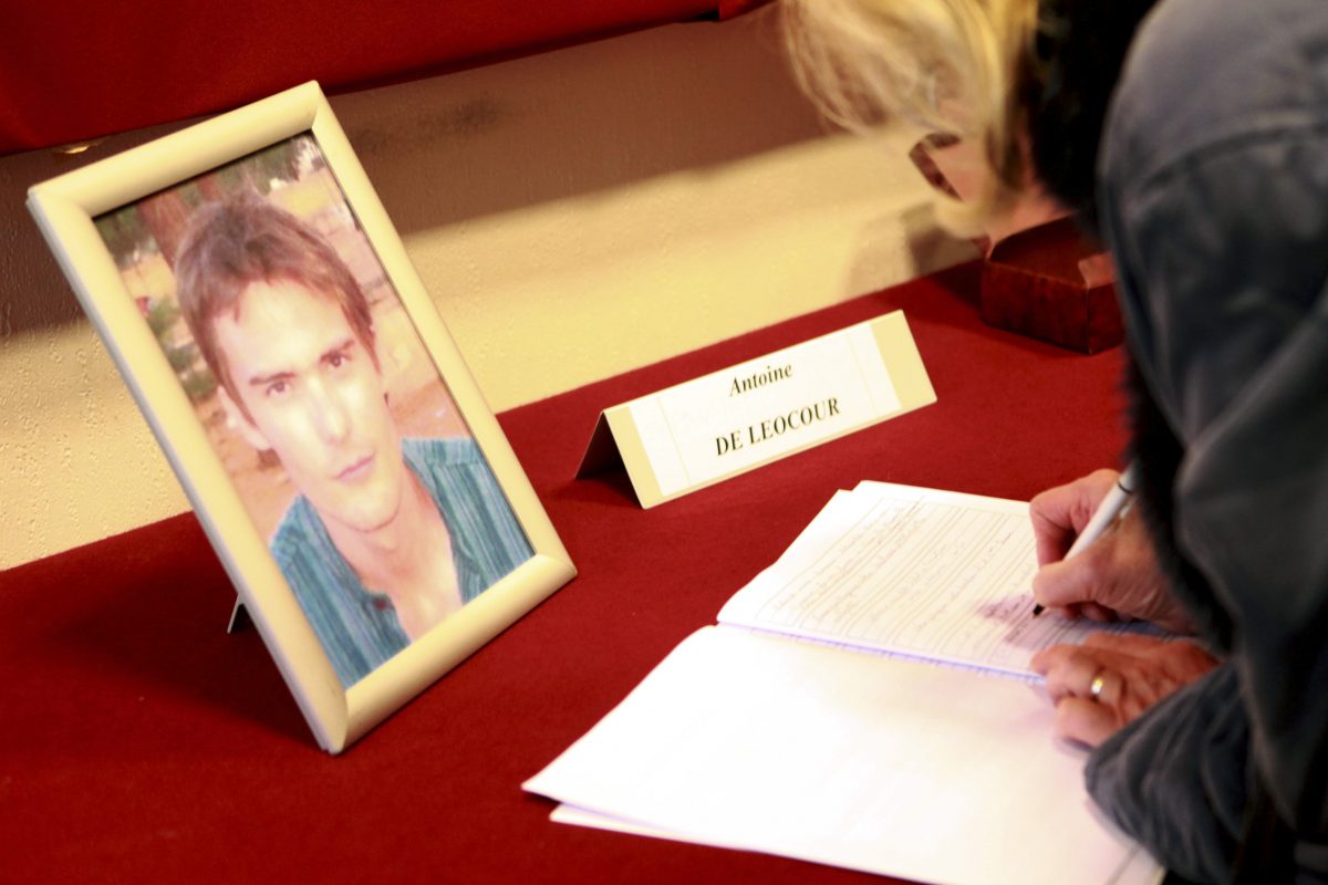 A woman signs condolence books in memory of Antoine de Leocour and Vincent Delory at Linselles' city hall, northern France