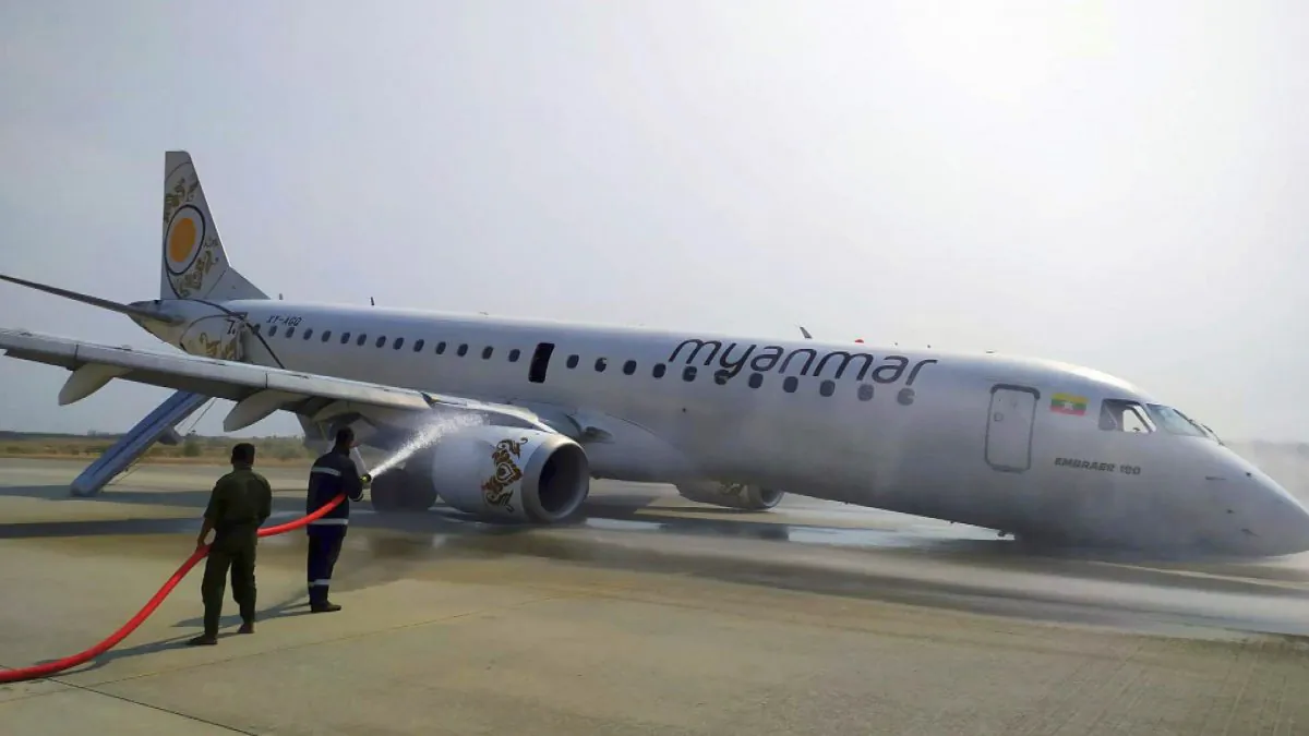 Firefighters work with hose on a plane of Myanmar National Airline (MNA) after an accident at Mandalay International airport in Mandalay, Myanmar on May 12, 2019. (Aung Thura via AP)