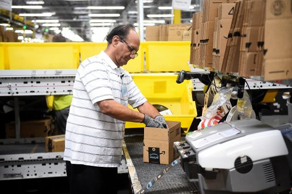Packing worker Hashmat Zubair fills a delivery box with products at the Amazon fulfillment center