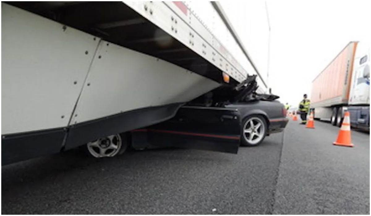 A wrecked mustang under a semi-trailer where it became wedged before being dragged for half a mile down the I-69 highway in Indiana on May 12, 2019. (Indiana State Police)