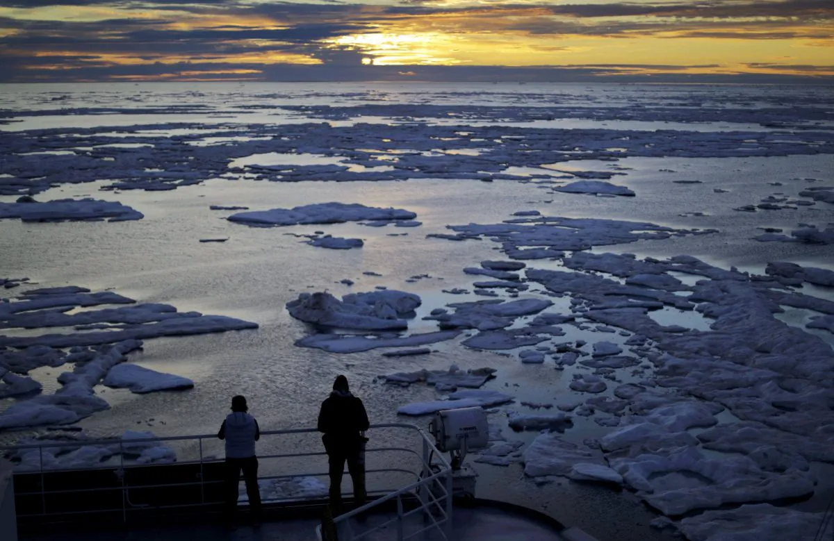 Researchers look out from the Finnish icebreaker MSV Nordica as the sun sets over sea ice in the Victoria Strait along the Northwest Passage in the Canadian Arctic Archipelago. (AP Photo/David Goldman, File)