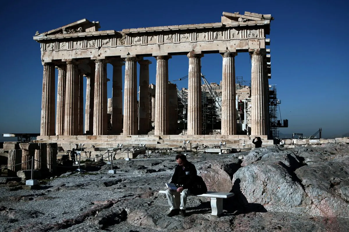 A man reads a book in front of the Parthenon temple on the Acropolis hill in Athens on Feb. 21, 2015. (ANGELOS TZORTZINIS/AFP/Getty Images)