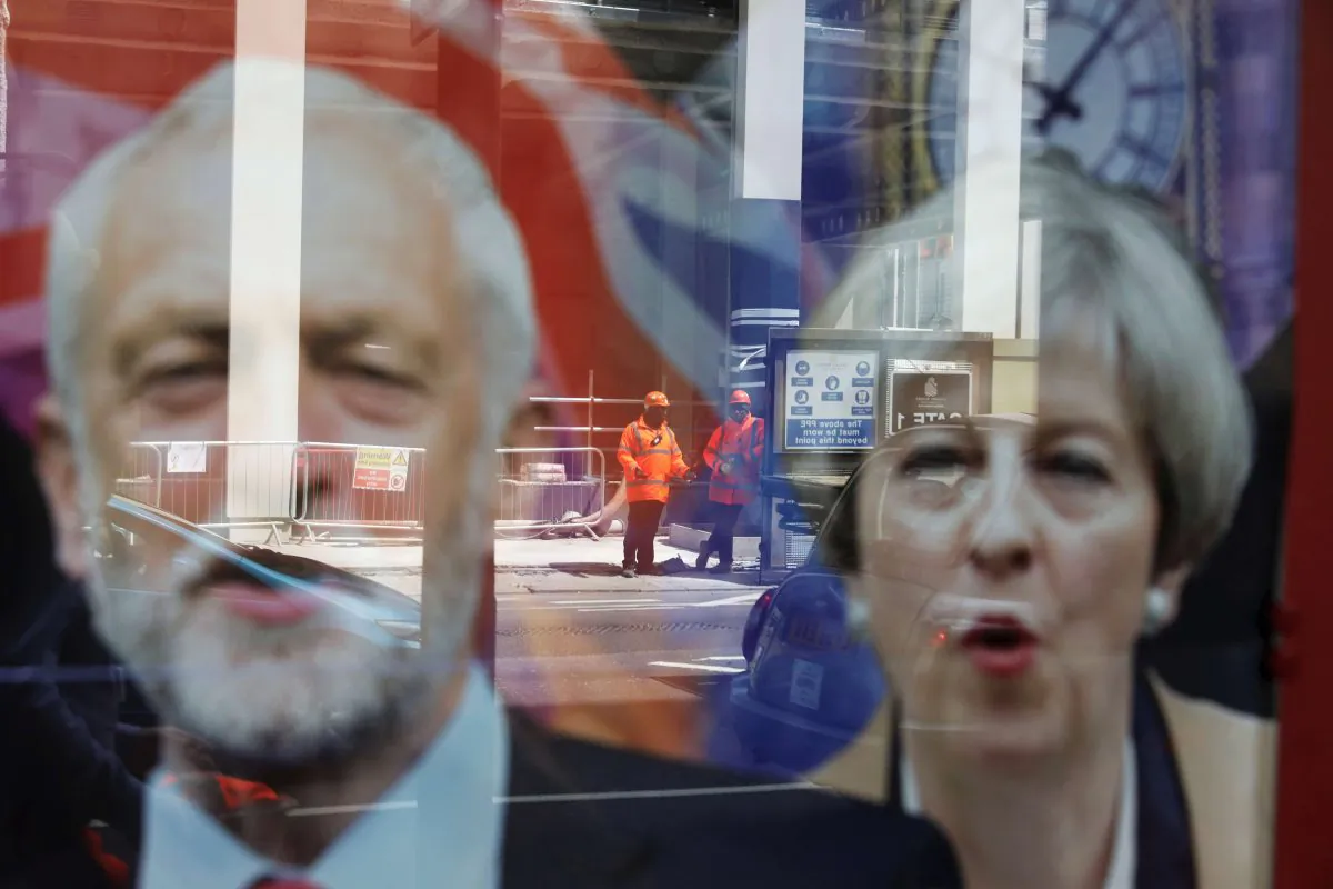 Workers in protective equipment are reflected in the window of a betting shop with a display inviting customers to place bets on the result of the general election with images of Britain's Prime Minister Theresa May and opposition Labour Party leader Jeremy Corbyn, in London on June 7, 2017. (Marko Djurica/Reuters)