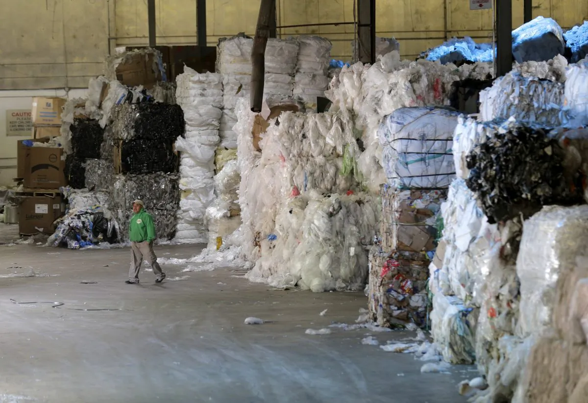 A man walks under towers of recyclables at a GDB International warehouse in Monmouth Junction, N.J. on May 7, 2019. (AP Photo/Seth Wenig)