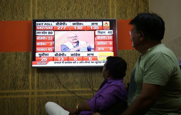 Men look at a television screen showing exit poll results