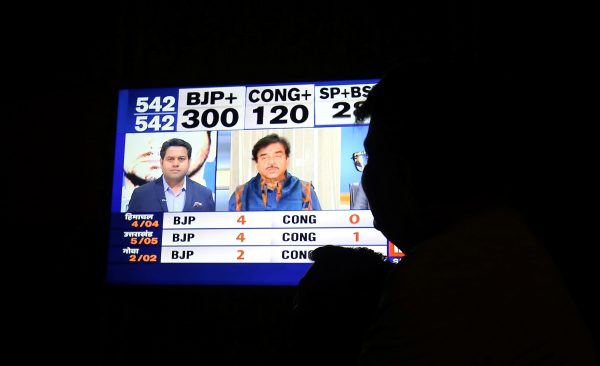 A man looks at a television screen showing exit poll results
