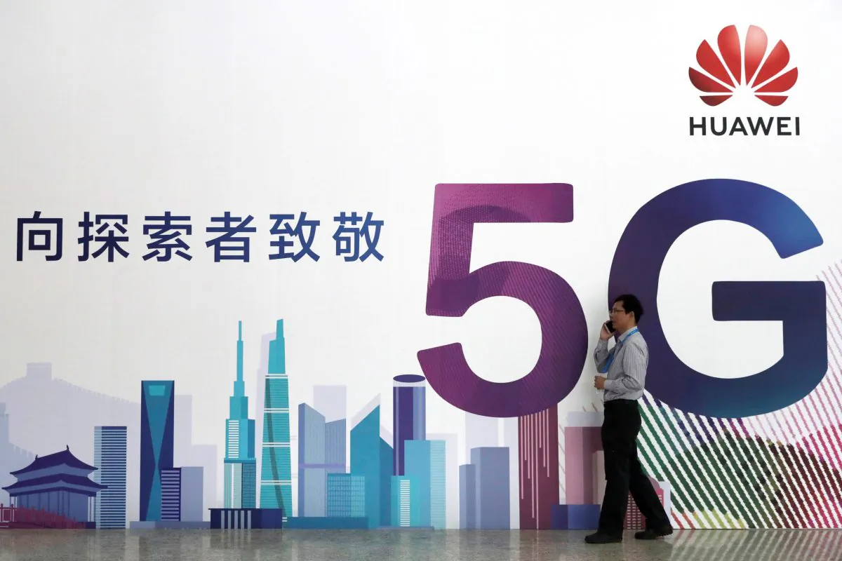 A man talks on his mobile phone beside Huawei's billboard featuring 5G technology at the PT Expo in Beijing on Sept. 26, 2018. (Reuters)
