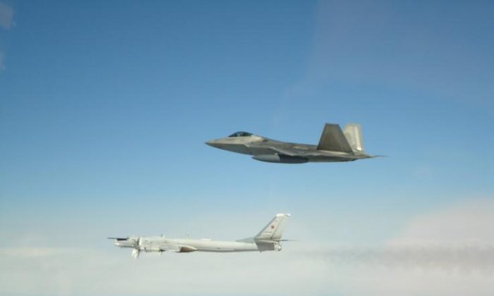 A Russian Tupolev Tu-95 strategic bomber and missile carrier (L) is seen being accompanied by a U.S. F-22 fighter jet in international airspace off the coast of Alaska in a file photo. (NORAD)