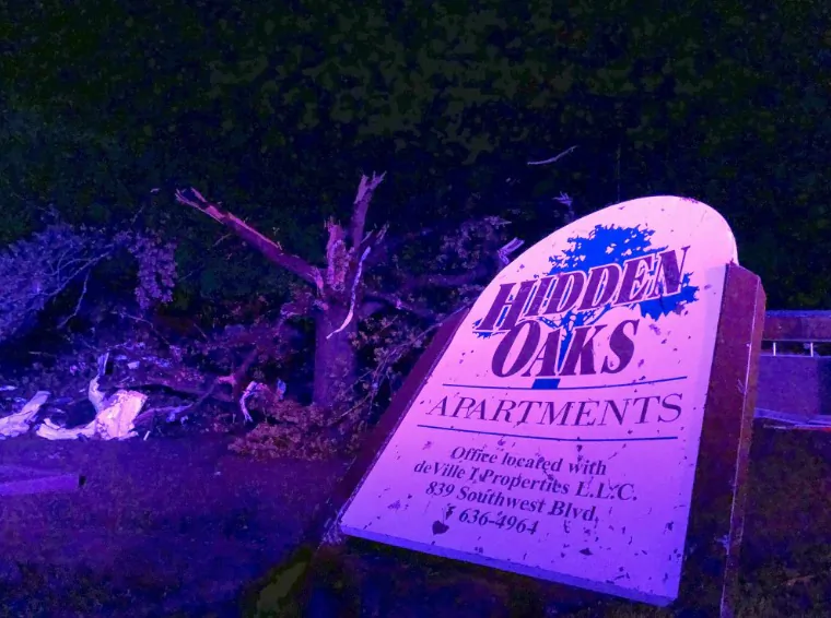 The sign for the Hidden Oaks apartment complex in Jefferson City Missouri stands bent on May 23, 2019, from an apparent tornado in front of a tree that was ripped apart. (David A. Lieb/AP Photo)