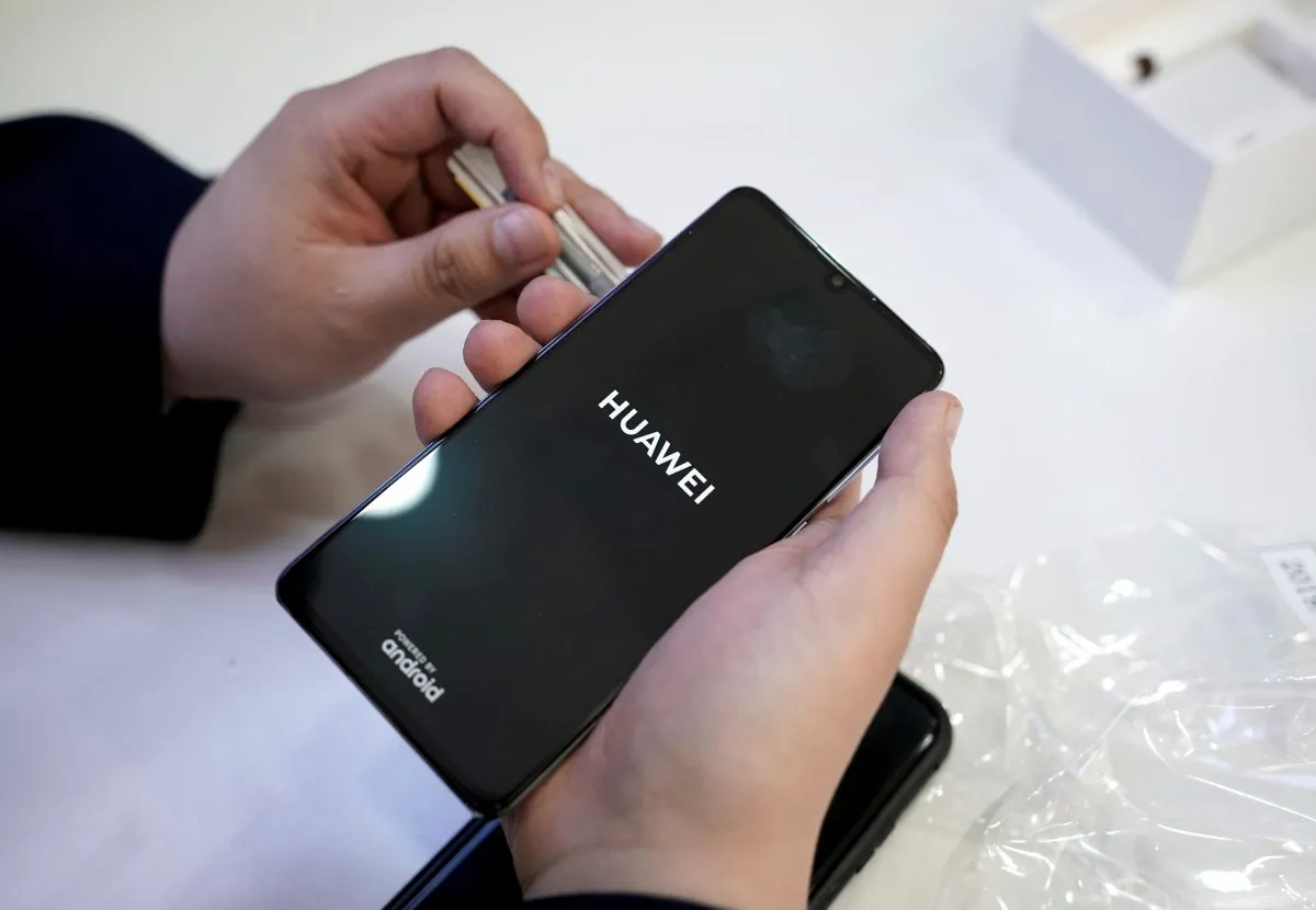 A salesman turns on a new Huawei P30 smartphone for a customer after Huawei's P30 and P30 Pro went on sale at a Huawei store in Beijing on April 11, 2019. (Jason Lee/Reuters)