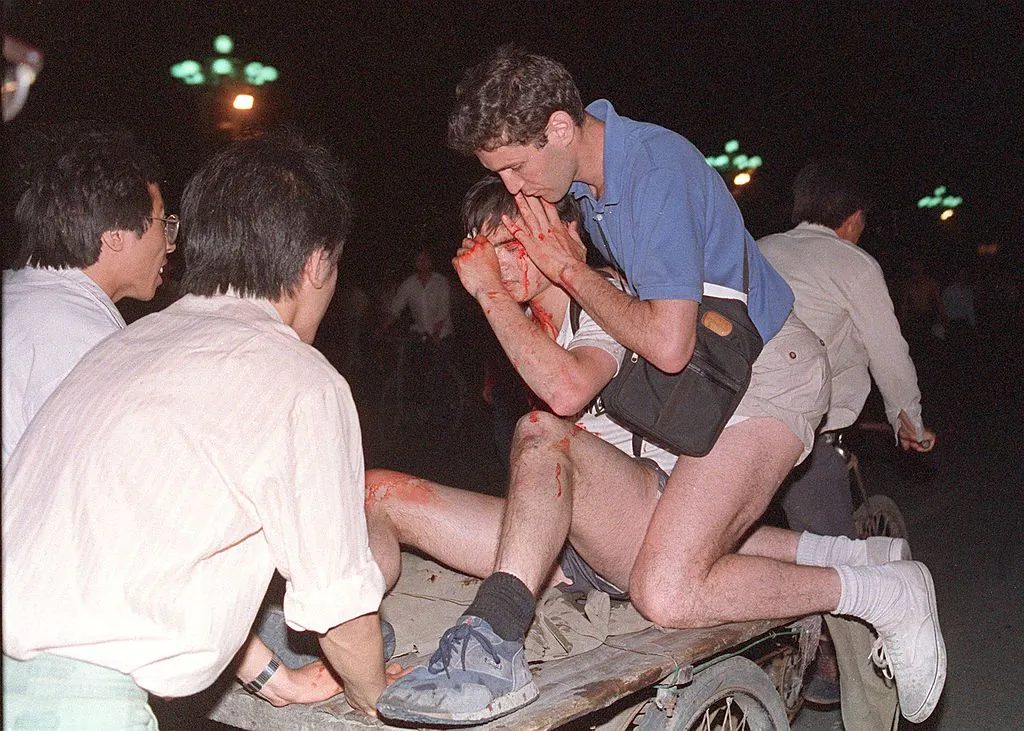 An unidentified foreign journalist (2nd-R) is carried out from the clash site between the army and students near Tiananmen Square in Beijing on June 4, 1989. (Tommy Cheng/AFP/Getty Images)