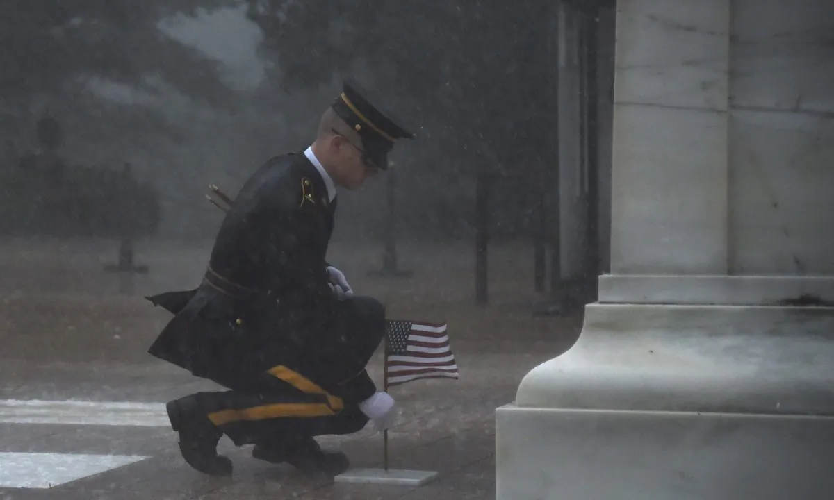 A sentinel endures a severe thunderstorm to place a small American flag at the grave of an unknown soldier. (U.S. Army photo by Sgt. Maryam Treece/3d U.S. Infantry Regiment)