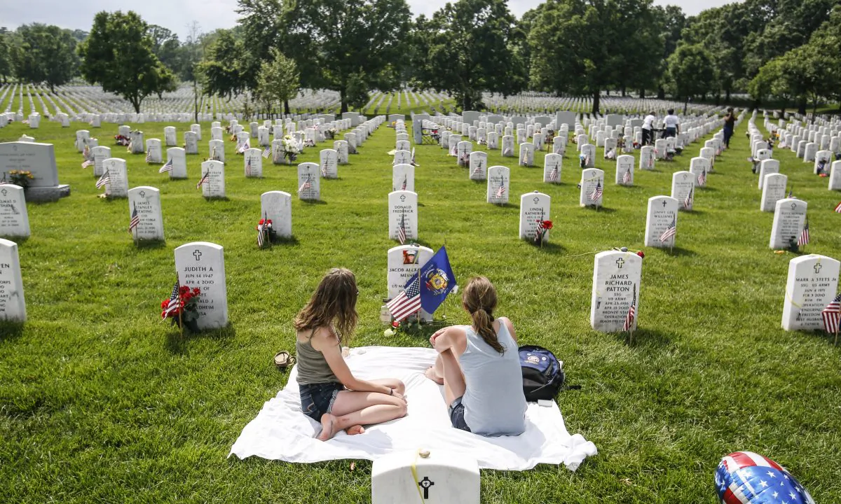 Krista Meinert (R), mother, and Randy Meinert, sister of Jacob Alexander Meinert, LCPL U.S. Marine Corps, sit at his grave in Arlington Cemetery in Arlington, Va., on May 26, 2019. (Samira Bouaou/The Epoch Times)