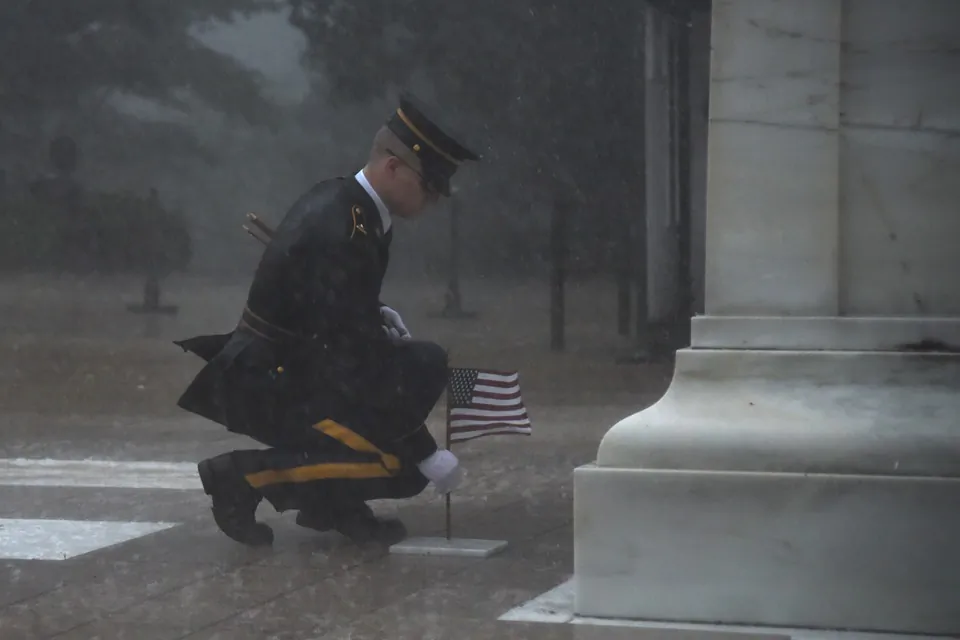 The soldier was seen placing down American flags as winds howled and torrential rain fell in Arlington, Virginia. (3rd U.S. Infantry Regiment)