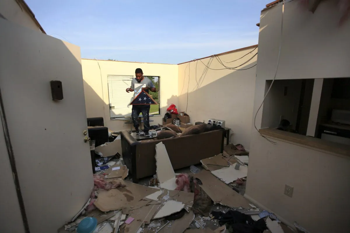 Carl Shackleford Jr. carries his father's memorial flag out of a tornado damaged apartment at the Westbrooke Village Apartment complex in Trotwood, Ohio, on May 28, 2019. (Doral Chenoweth III/The Columbus Dispatch via AP)
