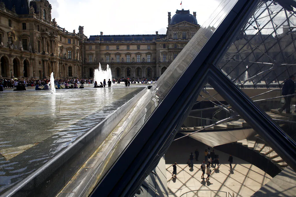 Tourists walk in the pyramid of the Louvre museum as it reopens, Paris, on May 29, 2019. (Thibault Camus/AP Photo)