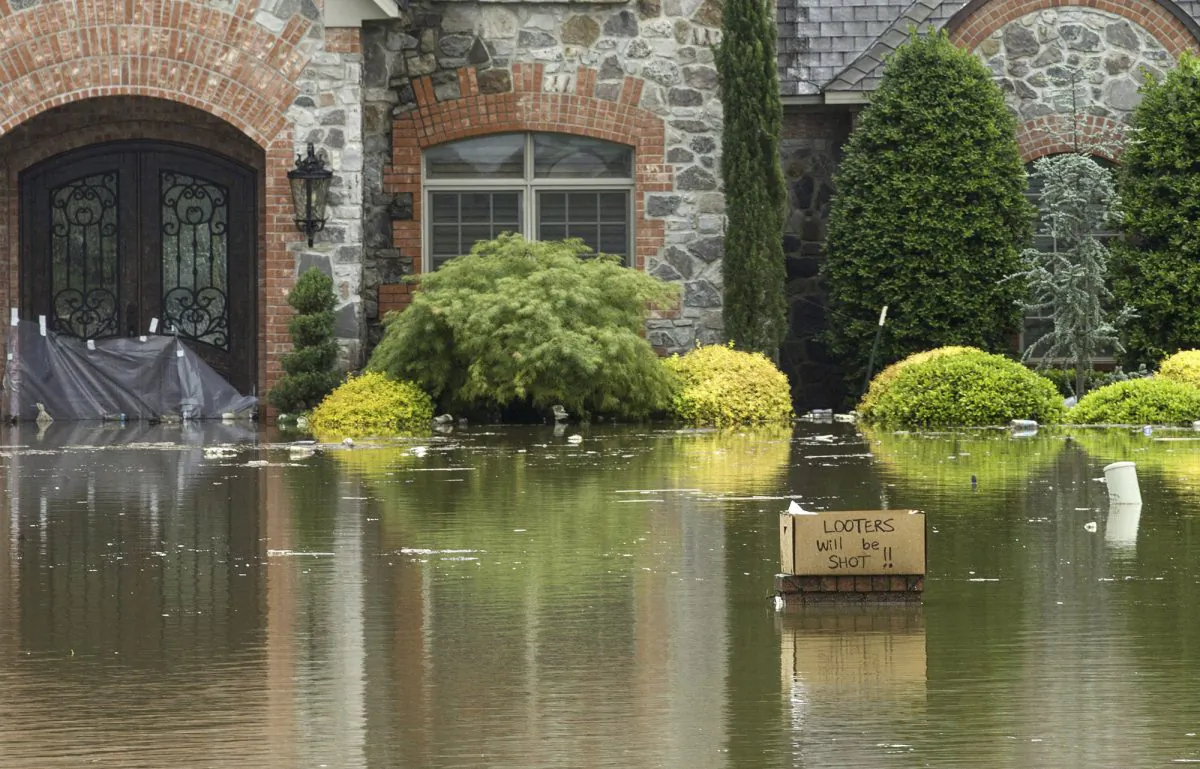 A sign reading "Looters will be shot!!" sits in front of a flooded home on Turtle Bay in Fort Smith, Ark., on May 29, 2019. (Ben Goff/The Northwest Arkansas Democrat-Gazette via AP)