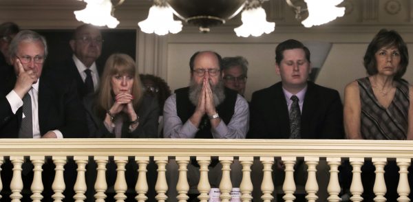 Rob Spencer, center, of Concord, N.H. pauses in prayer