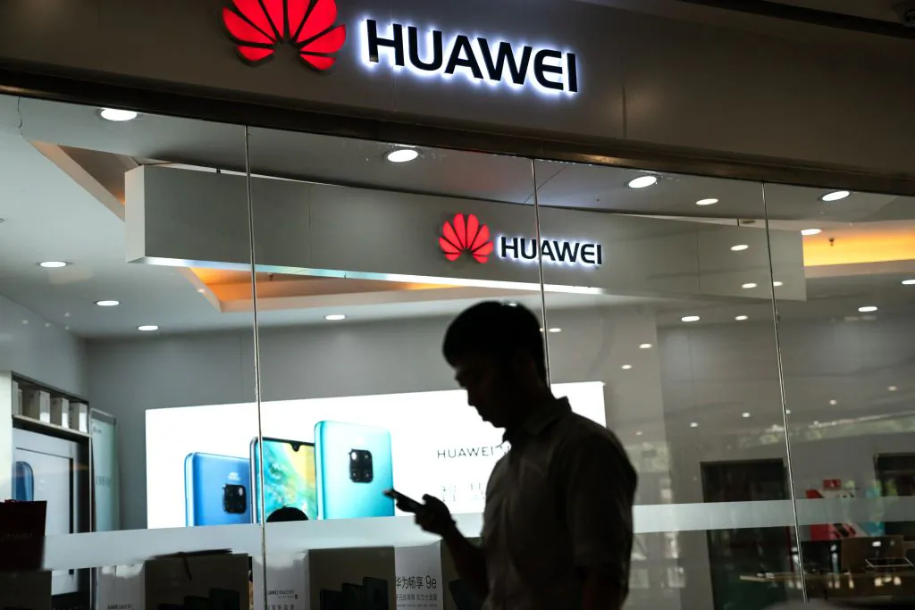A man walks past a Huawei logo displayed at a retail store in Beijing on May 23, 2019. (Fred Dufour/AFP/Getty Images)