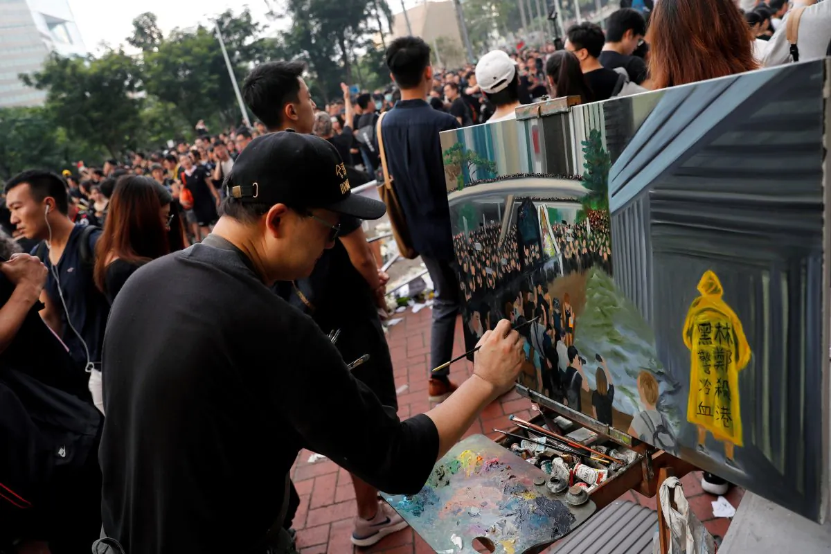 Artist Perry Dino paints a scene from protests against the extradition bill, in Hong Kong, on June 16, 2019. (REUTERS/Tyrone Siu)