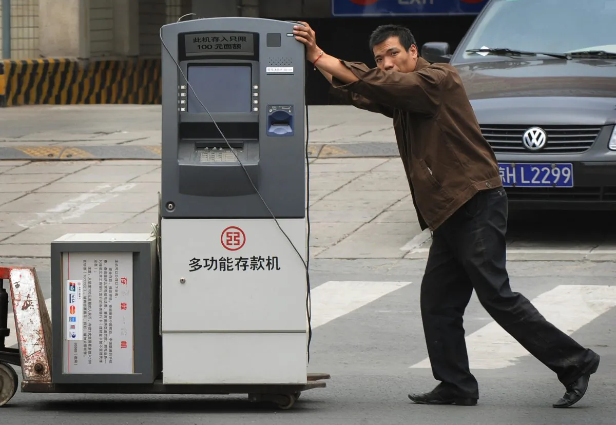 A worker wheels a bank teller machine on the streets of Beijing on June 18, 2008. (MARK RALSTON/AFP/Getty Images)