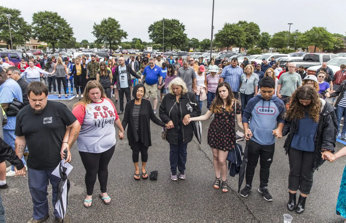Participants pray together with holding hands during the prayer vigil at Strawbridge Marketplace, Virginia Beach, Va., Saturday, June 1, after the mass shooting, which killed 12 people. (Daniel Sangjib Min/Richmond Times-Dispatch via AP)