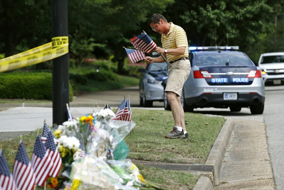 Rich Lindgren places American flags at a makeshift memorial at the edge of a police cordon in front of a municipal building that was the scene of a shooting in Virginia Beach, Va., on June 1, 2019. (Patrick Semansky/AP Photo)