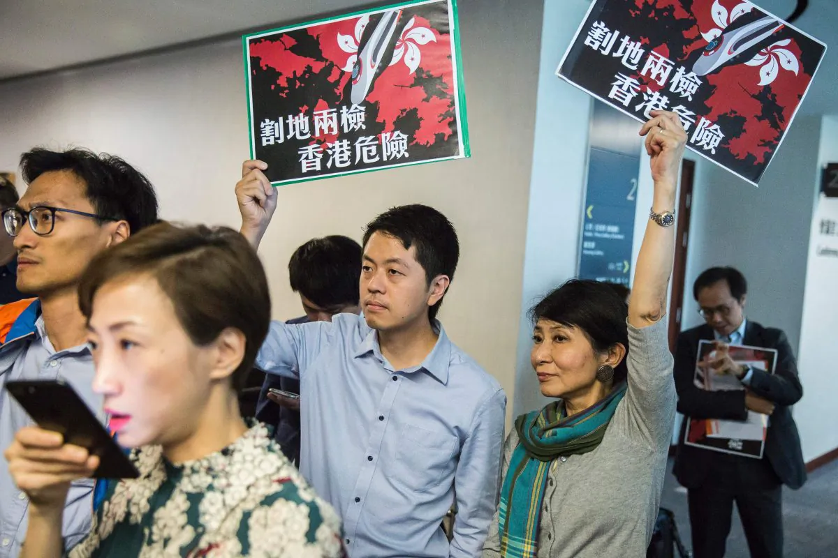Pro-democracy lawmakers Ted Hui (C) of the Democratic Party and Claudia Mo (centre R) of the Civic Party hold signs reading "ceding land with co-location puts Hong Kong in danger" at the Legislative Council building in Hong Kong on Aug. 3, 2017. (Isaac Lawrence/AFP/Getty Images)