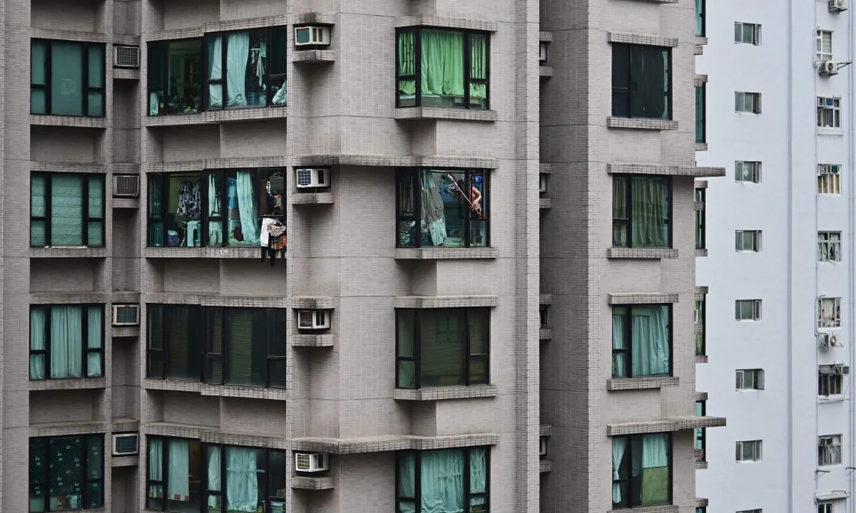 A woman reaching out of a high rise building in China. (Anthony Wallace/AFP/Getty Images)