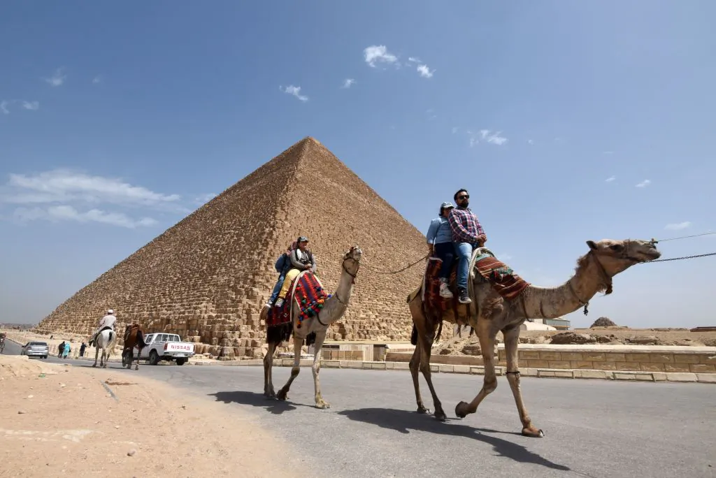 Tourists on camels ride past a pyramid at Cairo's northern Giza province on March 29, 2017. (Mohamed El-Shahed/AFP/Getty Images)