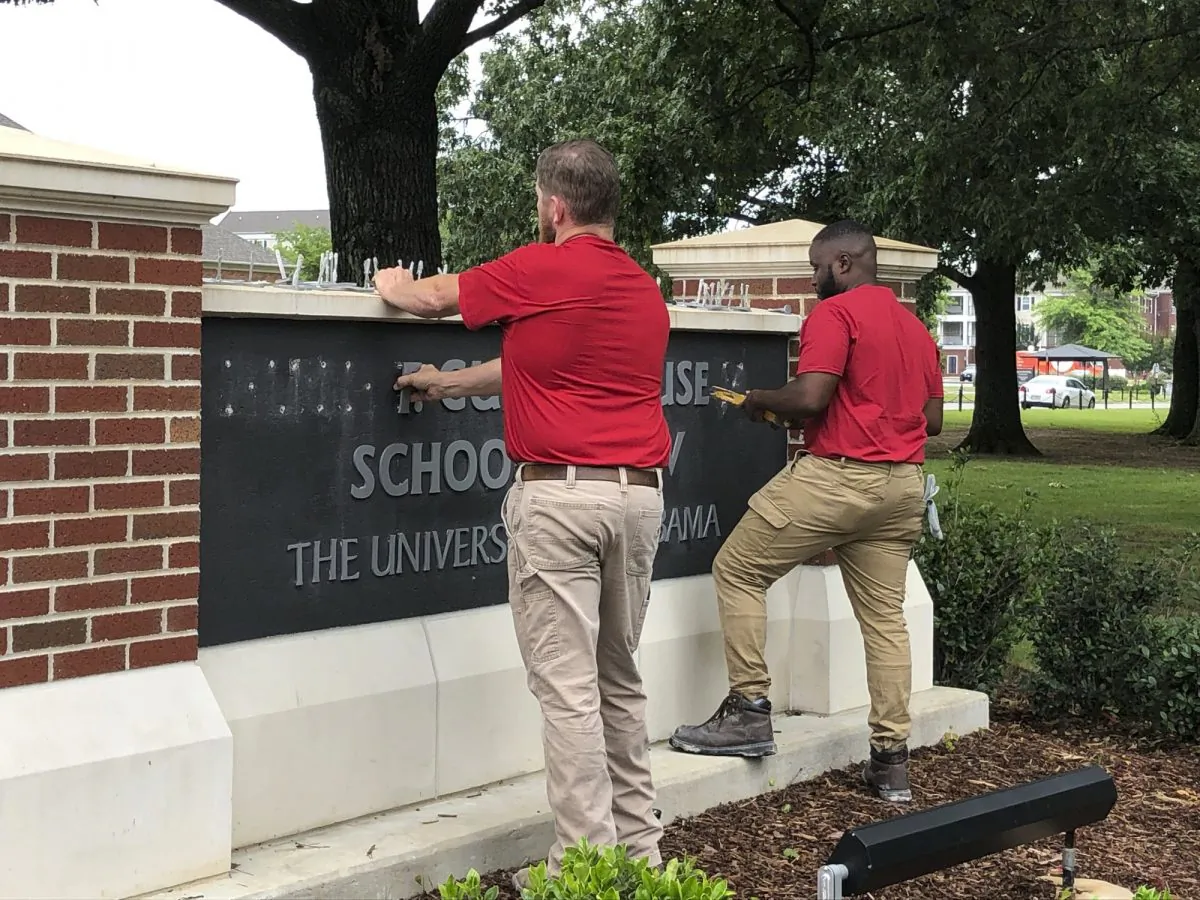 University of Alabama employees remove the name of Hugh F. Culverhouse Jr. off the School of Law sign in Tuscaloosa, Ala., on June 7, 2019. (Blake Paterson/Photo/AP)