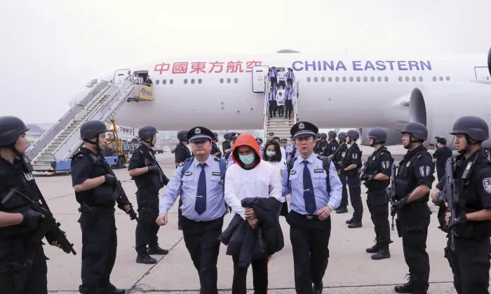 Police escort alleged criminal suspects as they get off a plane at Beijing Capital International Airport on June 7, 2019. (Yin Gang/Xinhua via AP)