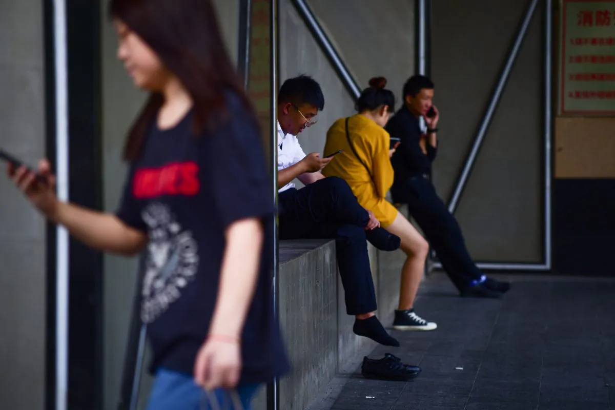 People look at their mobile phone outside a mall in Beijing on June 5, 2018. (Wang Zhao/AFP/Getty Images)