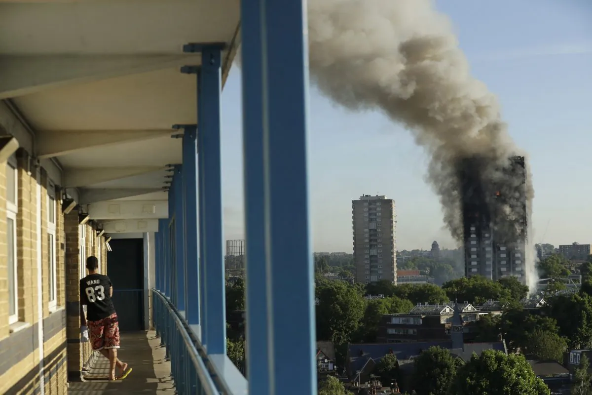 A resident in a nearby building watches smoke rise from a building on fire in London on June 14, 2017. (Matt Dunham, File photo via AP)