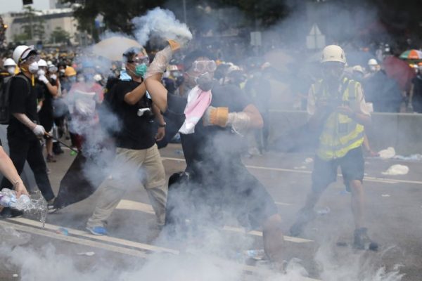 A demonstrator throws a canister of tear gas back towards the police outside the Legislative Council