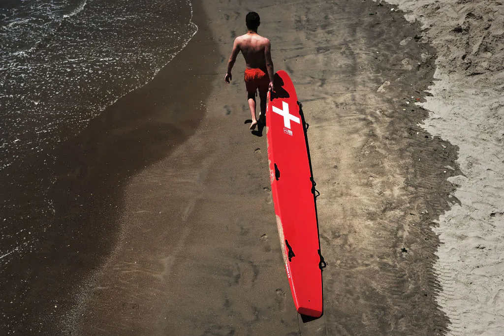 In this file image, a lifeguard walks the beach at Coney Island with a rescue board in the Brooklyn borough of New York City on July 5, 2018. (Spencer Platt/Getty Images)