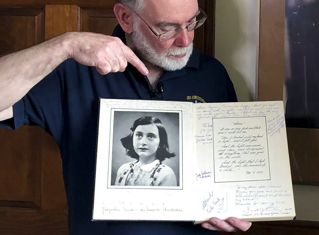 In this June 7, 2019 photo, Ryan Cooper holds a 1972 portion of a diary that he wrote when he visited Otto Frank, the father of the famed Holocaust victim and diarist Anne Frank, at his home in Yarmouth, Mass. The diary includes a photo of Anne Frank and the autographs of other people he met who knew her. Cooper has donated a trove of letters and mementos he received from Otto Frank to the U.S. Holocaust Memorial Museum ahead of the 90th anniversary of Anne Frank's birthday. (Philip Marcelo/AP Photo)