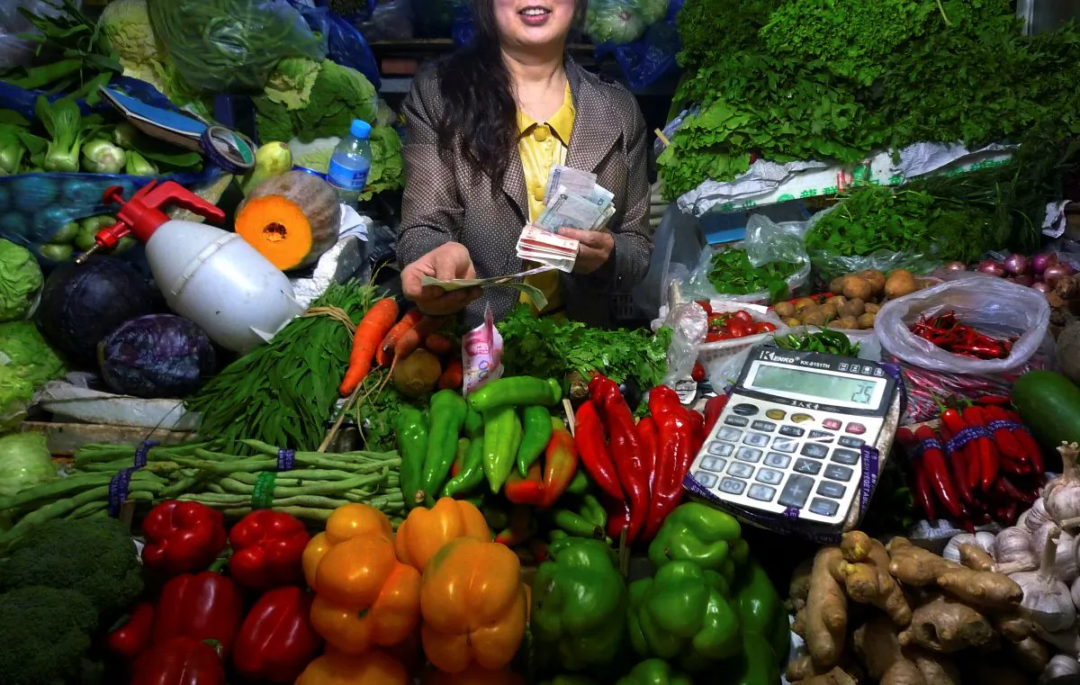 A fruit and vegetable stall owner uses a calculator to work out prices for a customer at a small market in central Beijing on July 7, 2011. (David Gray/Reuters)