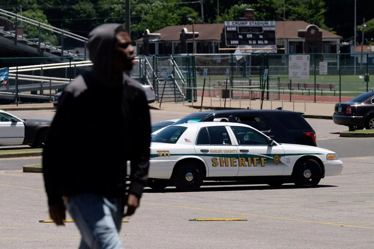 A young man walks in front of a police patrol parked in front of a high school a day after violent clashes between police and protesters broke out on streets overnight in Memphis, Tenn., on June 13, 2019. (Ricardo Arduengo/Reuters)