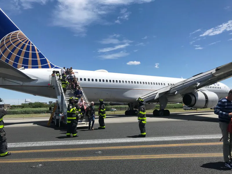 Emergency personnel help passengers off a plane after a United Airlines plane skidded off the runway after landing at Newark Liberty International Airport in Newark, N.J., on June 15, 2019. (Caroline Craddock via AP)