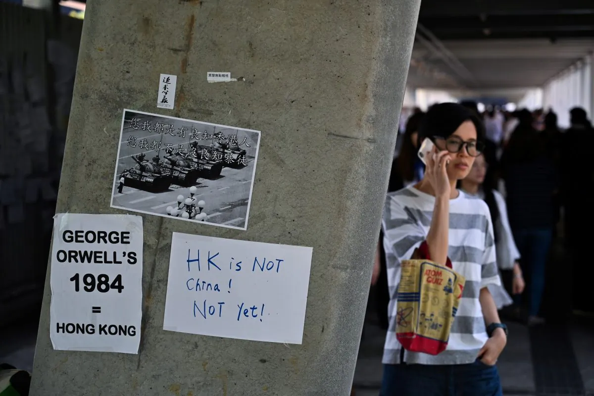 People walk past placards against a controversial extradition law proposal pasted on a wall near the Legislative Council Complex in Hong Kong on June 14, 2019. (Hector Retamal/AFP/Getty Images)