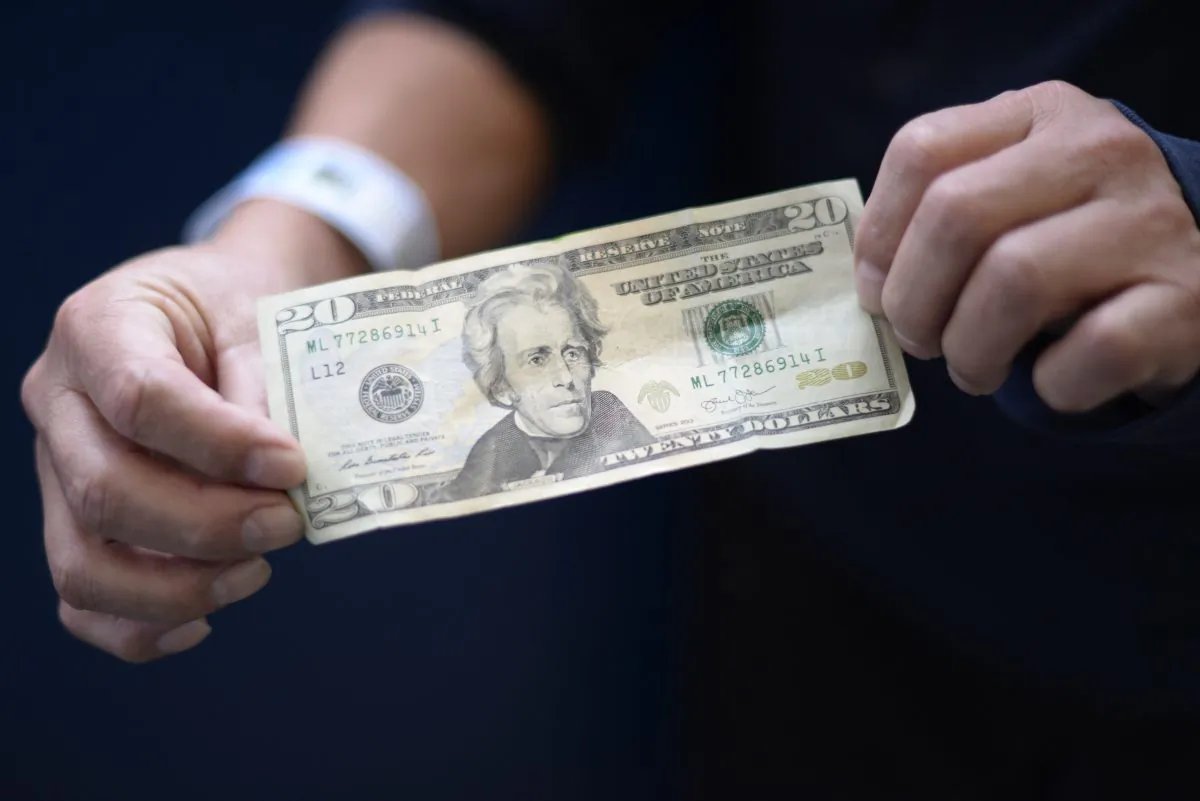 A member of a group of 228 immigrants deported from the United States shows a 20-dollar bill before exchanging it upon arrival at the Air Force base in Guatemala City on Jan. 10, 2018. JOHAN ORDONEZ/AFP/Getty Images