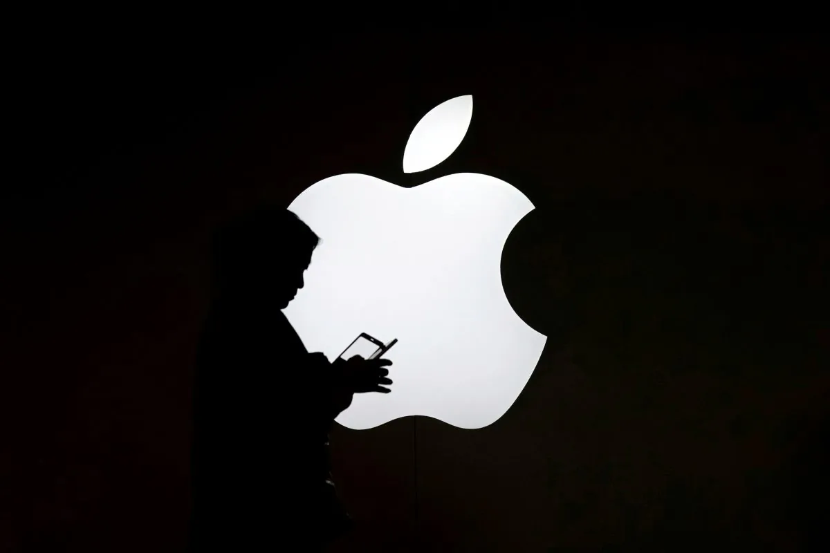 A woman looks at the screen of her mobile phone in front of an Apple logo outside its store in Shanghai, China on July 30, 2017. (Aly Song/Reuters)