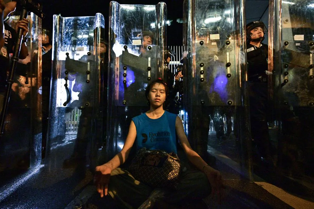 Lam Ka Lo meditates in front of a line of riot police standing guard with their shields outside the government headquarters in Hong Kong on June 12, 2019. (Anthony Wallace/AFP/Getty Images)